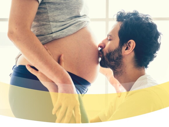 Schwangerschaftskalender das Wichtigste auf einen Blick. Mann küsst Babybauch.​